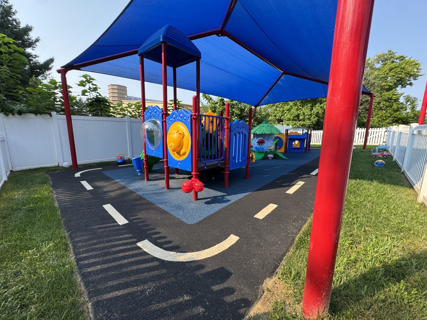 Creative Nursery playground in North Brunswick, NJ, poured-in-place rubber with a road-play design under blue shade sails