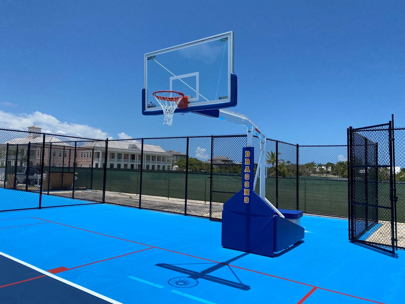 Padded portable basketball goal on a fenced blue court