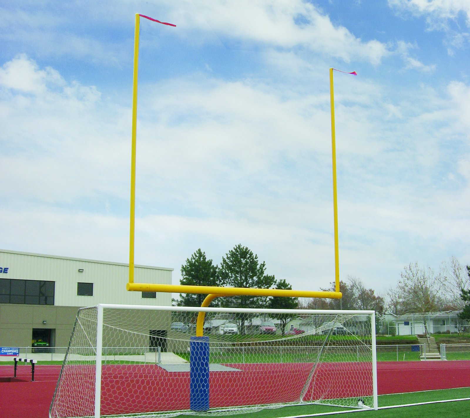 Yellow football goal post over a soccer goal on a school turf field