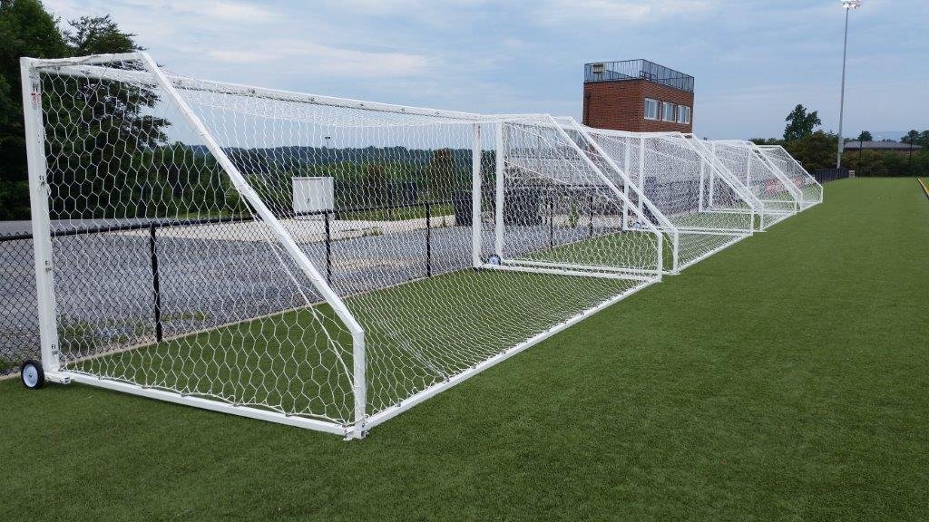 Row of white portable soccer goals lined up on a school turf field