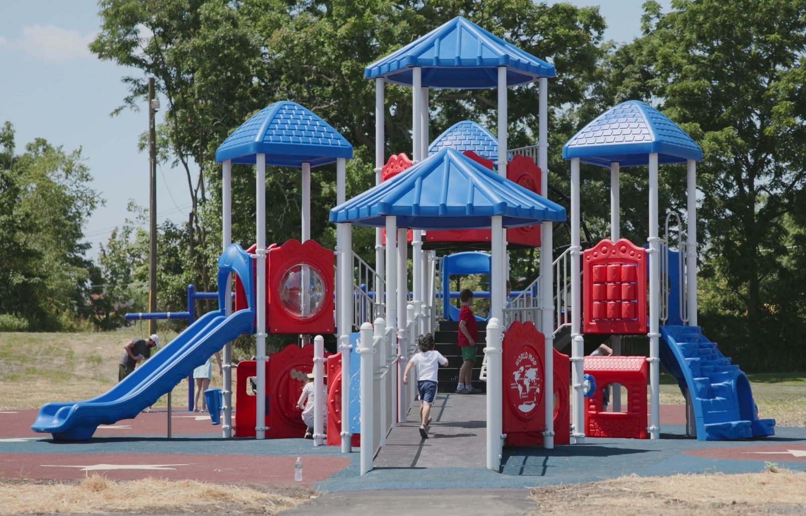 Commercial playground with blue roofs and an accessible ramp at Erie Street Park, Village of Goshen