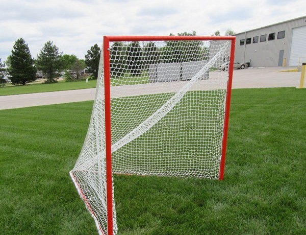 Red lacrosse goal with a white net standing on grass