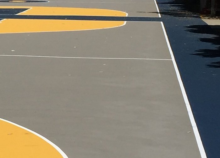 Grey acrylic basketball court with navy keys, yellow arcs and white painted lines
