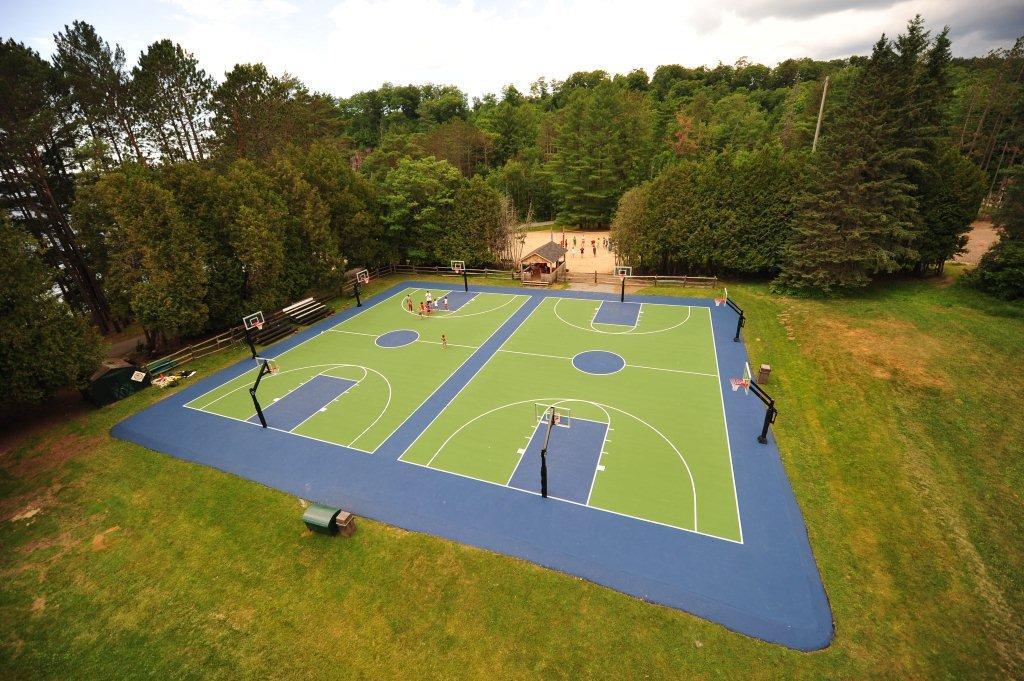Aerial view of a painted multi-court basketball complex surrounded by trees